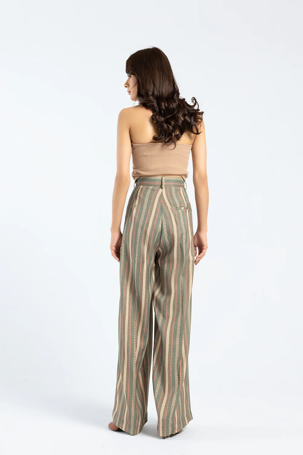 Side profile view showcasing the dramatic movement and architectural flared silhouette of the blue green striped palazzo pants.