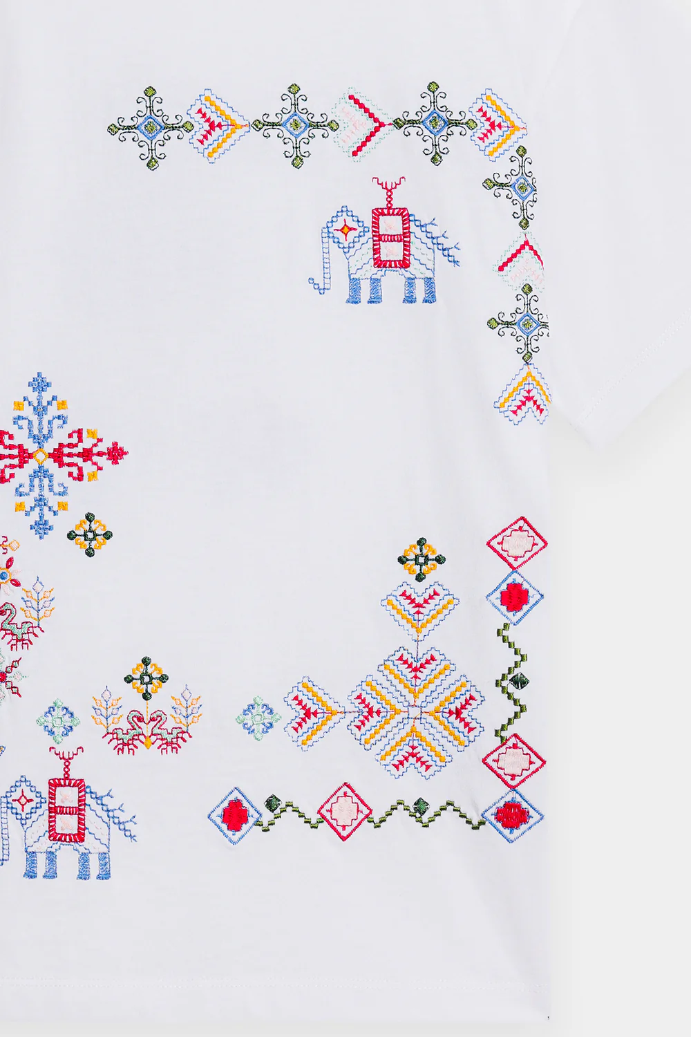 Close-up shot highlighting the intricate, multi-colored geometric and abstract threadwork on the premium crisp white textile.