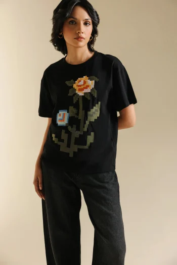 Front studio portrait of Biljiki jet black t-shirt featuring multi-colored pixelated floral embroidery on a 5'6 model.