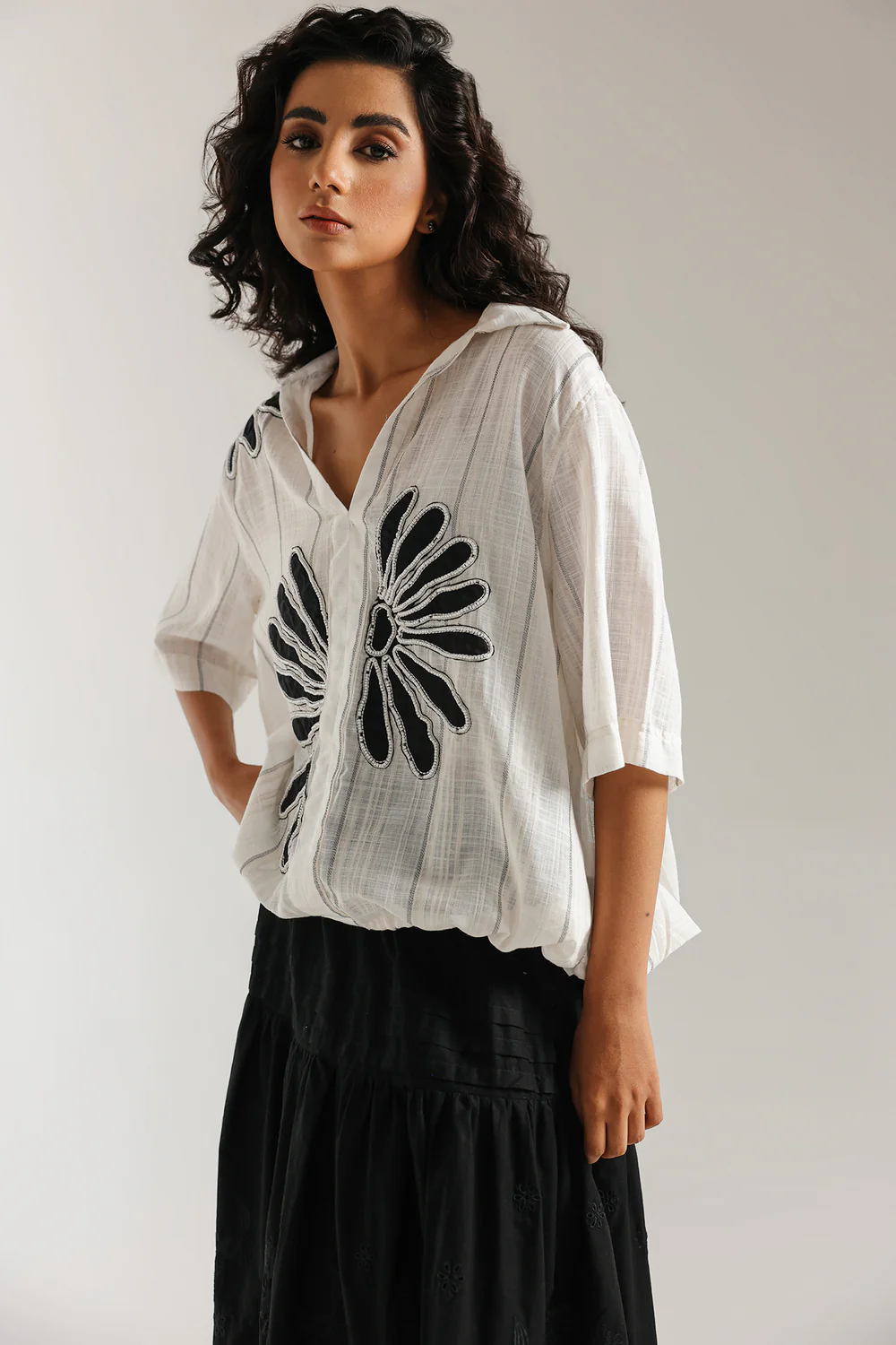 Front studio portrait of Biljiki jet black tiered blouse featuring a vibrant polychrome collage print on a 5'6 model.