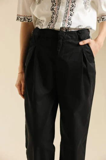 Front studio portrait of Biljiki jet black relaxed-fit pleated trousers on a 5'6 model.