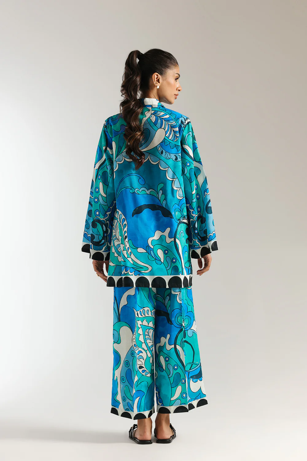 Back studio portrait of Biljiki vibrant blue-green artistic printed two-piece culotte set on a 5'6 model.