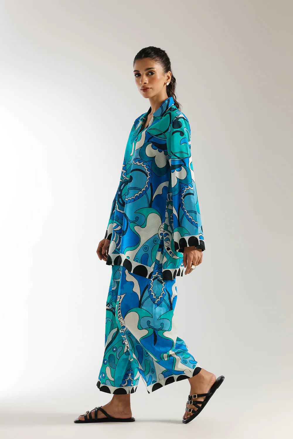 Side studio portrait of Biljiki vibrant blue-green artistic printed two-piece culotte set on a 5'6 model.