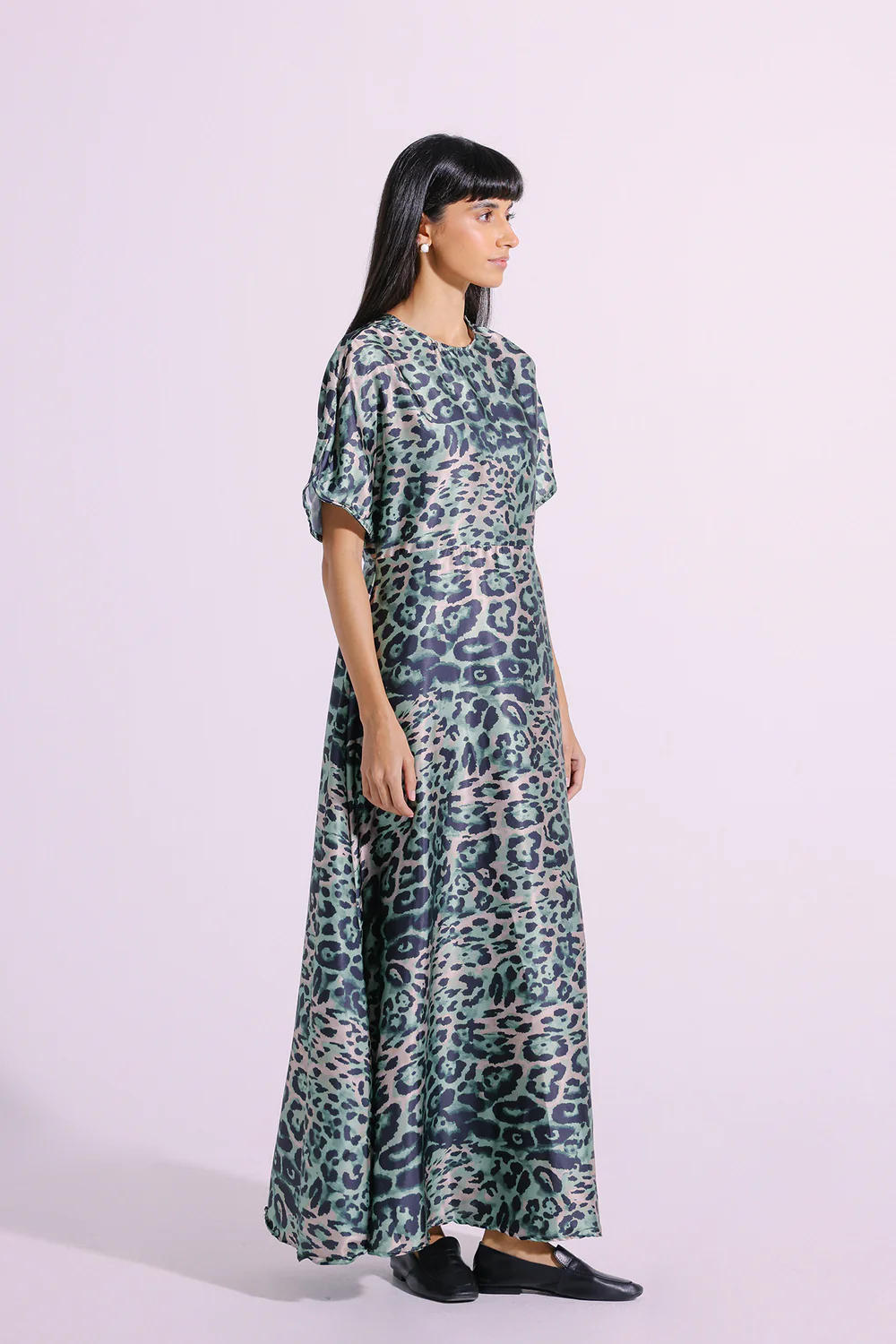 Lifestyle view showcasing the elongated silhouette and sweeping fluid movement of the contemporary green animal print dress.