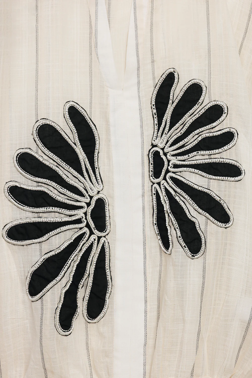 Close-up shot highlighting the vibrant illustrative print and the customizable tie detailing at the shoulder of the premium black blouse.