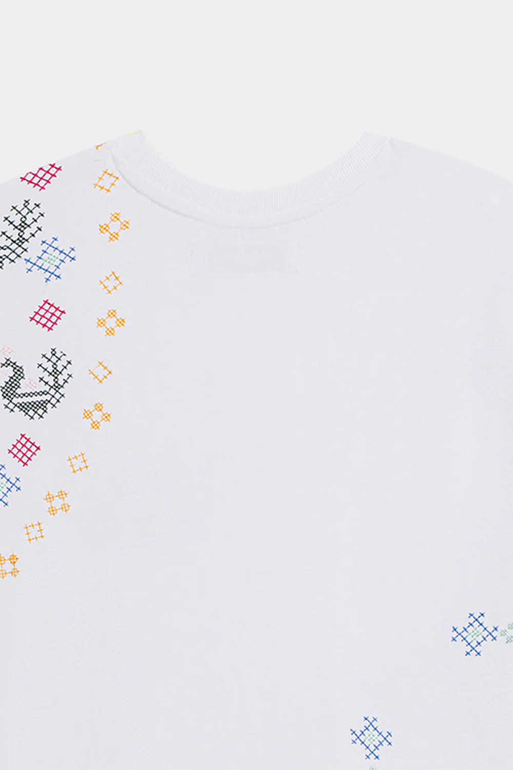 Close-up shot highlighting the intricate, multi-colored abstract and geometric threadwork on the premium optic white textile canvas.
