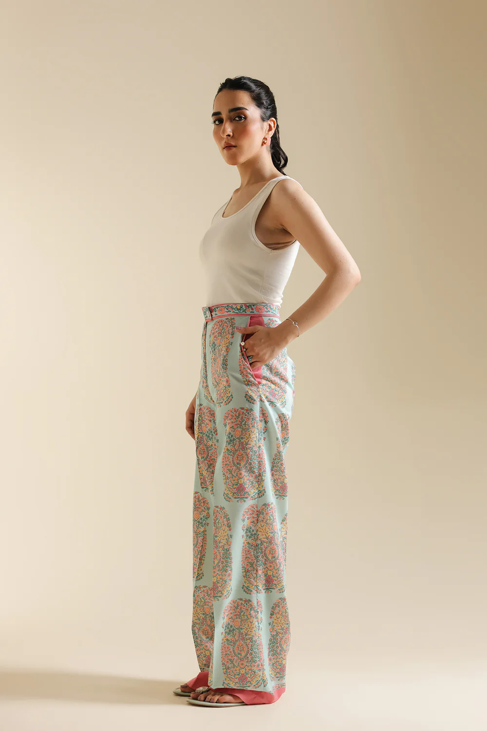 Side studio portrait of Biljiki pale pink contemporary trousers featuring a vibrant paisley print on a 5'6 model.
