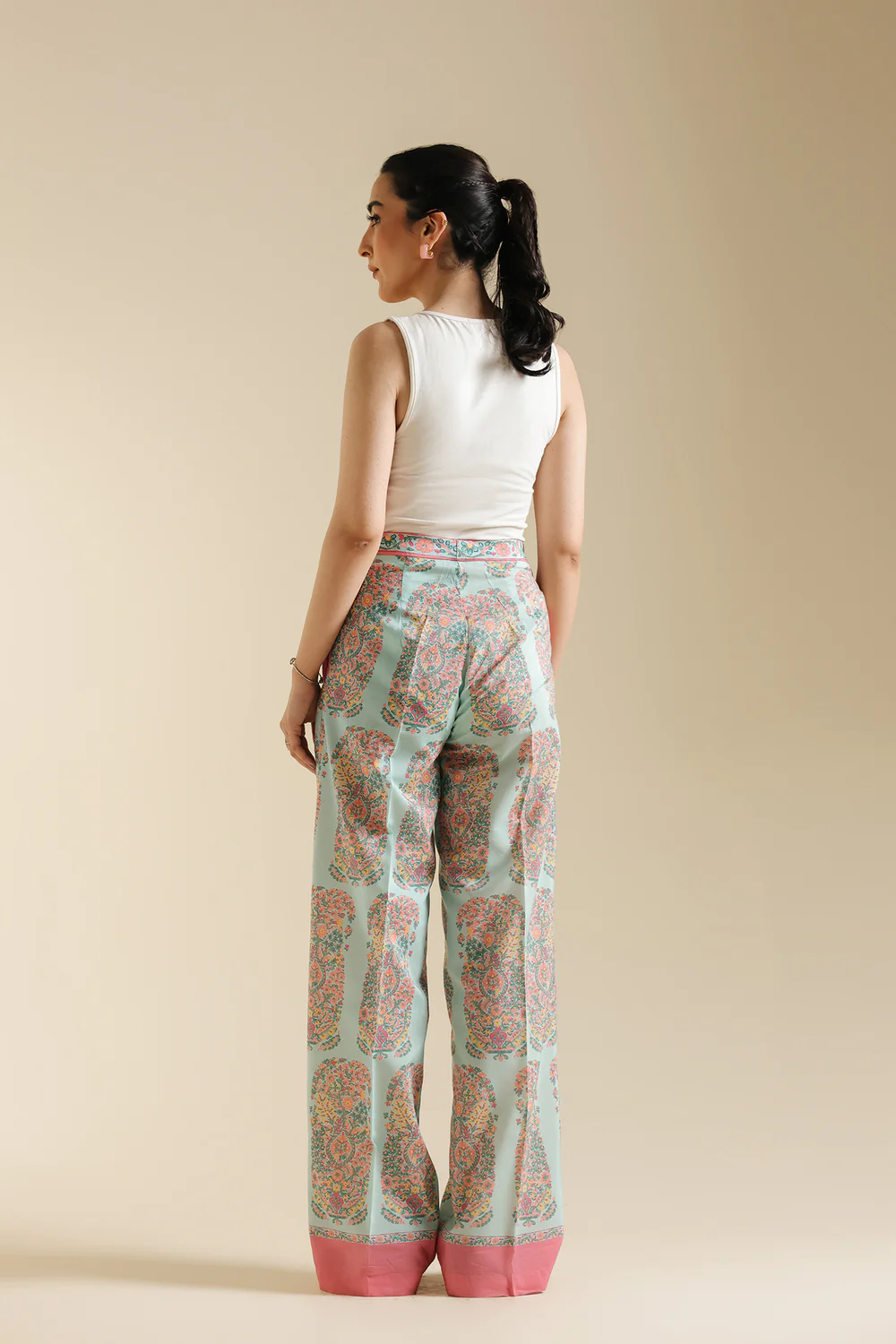 Back studio portrait of Biljiki pale pink contemporary trousers featuring a vibrant paisley print on a 5'6 model.