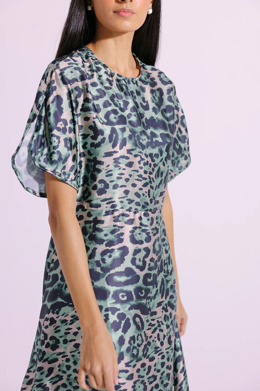 Close-up shot highlighting the vibrant animal motif and lustrous, silken drape of the premium green poly-shamooz fabric.