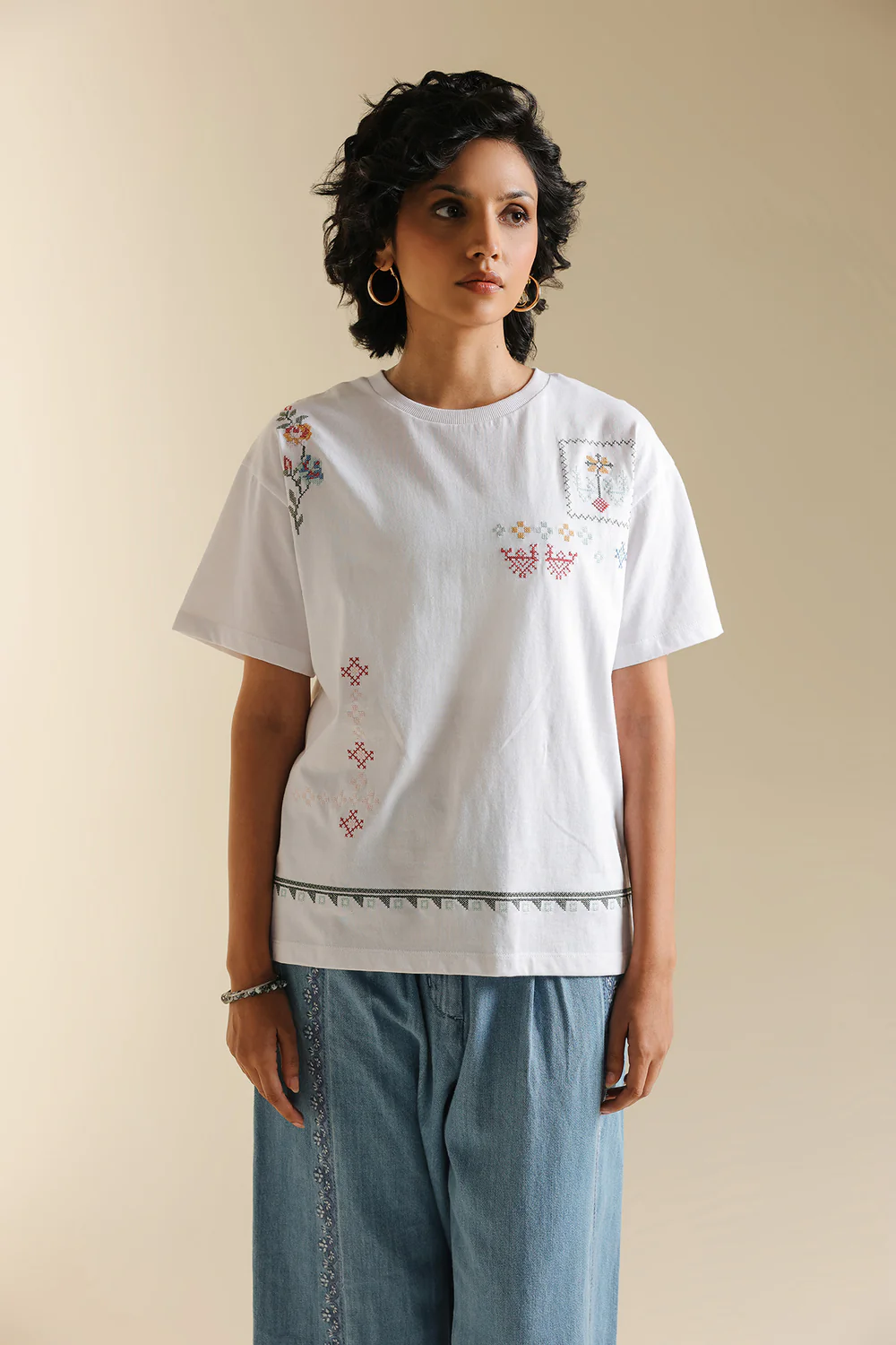 Front studio portrait of Biljiki optic white t-shirt featuring multi-colored abstract embroidery on a 5'6 model.