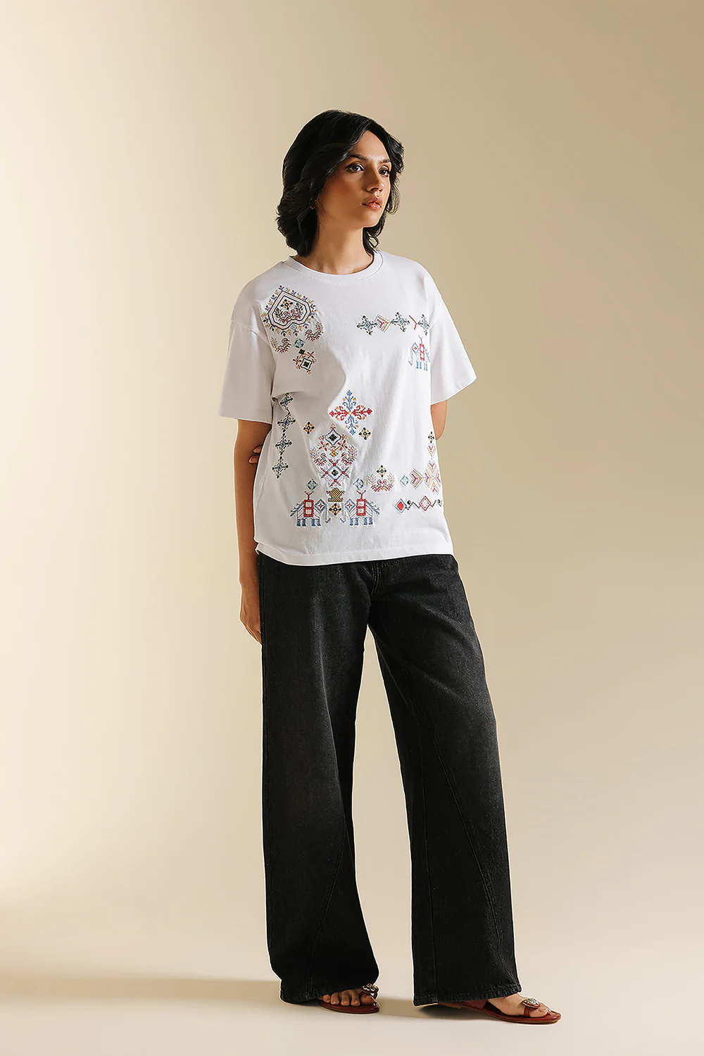 Front studio portrait of Biljiki crisp white t-shirt featuring multi-colored geometric embroidery on a 5'6 model.