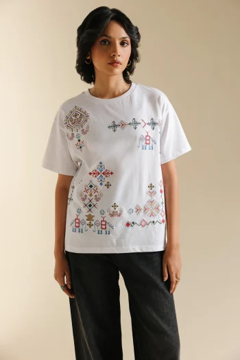 Front studio portrait of Biljiki crisp white t-shirt featuring multi-colored geometric embroidery on a 5'6 model.