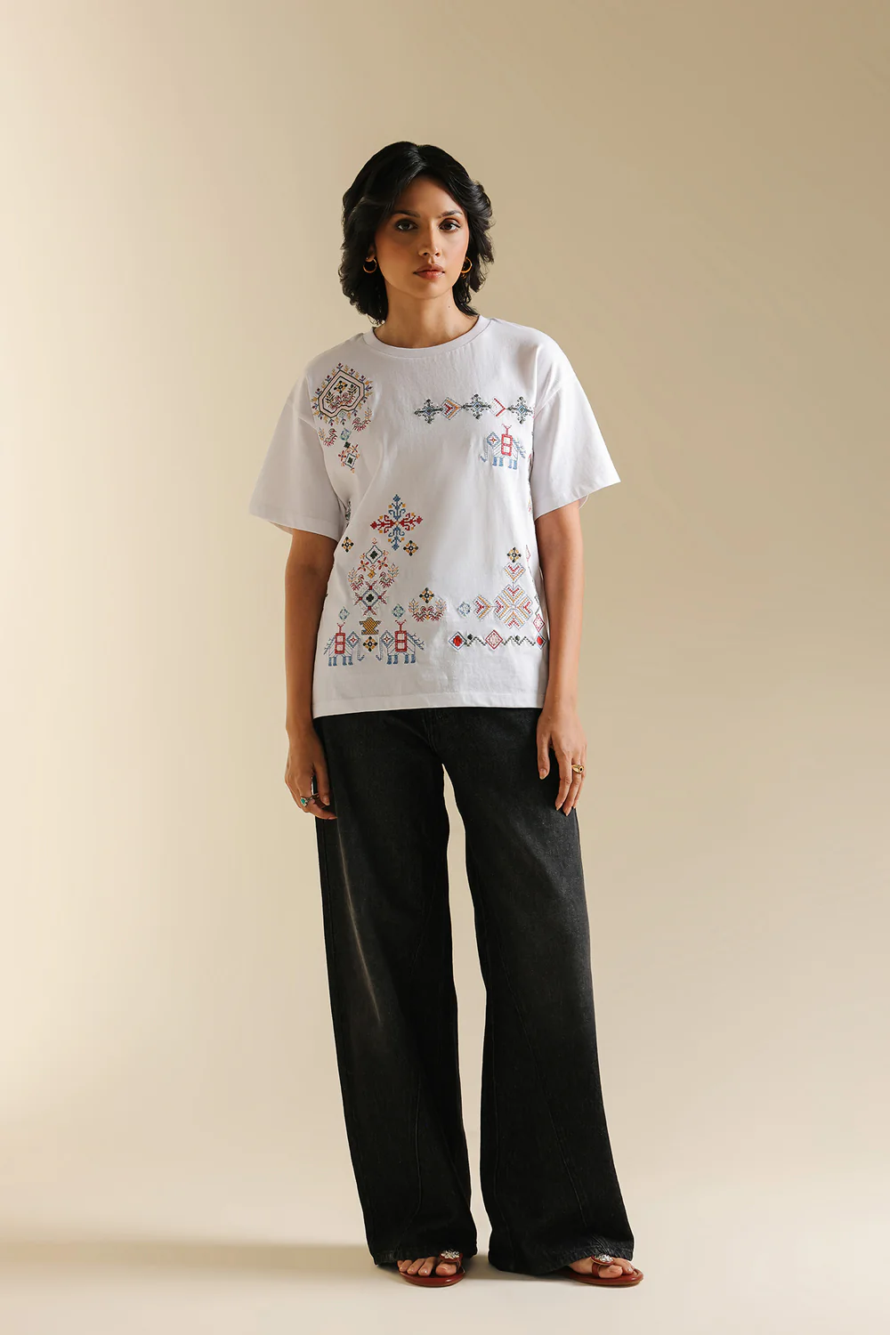 Front studio portrait of Biljiki crisp white t-shirt featuring multi-colored geometric embroidery on a 5'6 model.