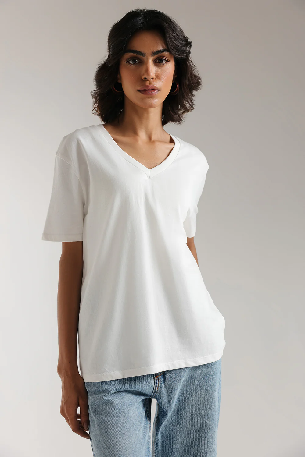 Close-up shot highlighting the sharp, architectural V-neckline and smooth, solid drape of the premium white textile.